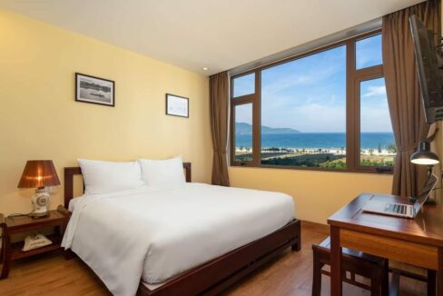 A hotel room with a breathtaking view of the ocean and majestic mountains in the background.