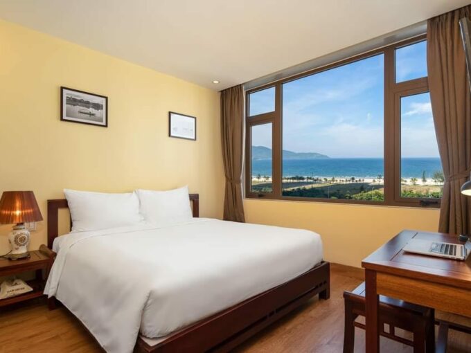 A hotel room with a breathtaking view of the ocean and majestic mountains in the background.